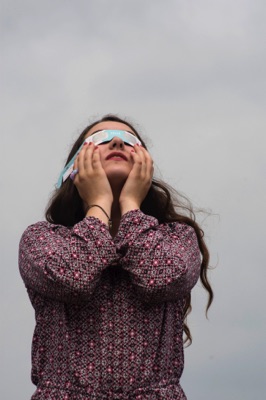 Woman with eclipse glasses looking up